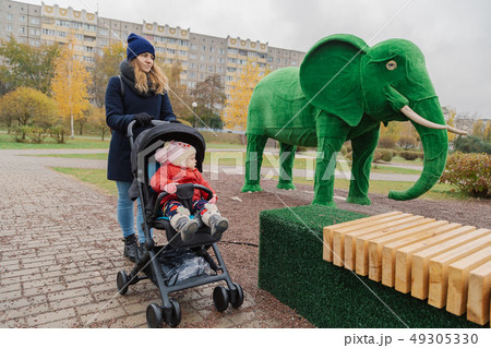 A woman walks in the park with a stroller and a A woman walks in the park with a stroller and a 49305330