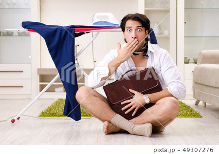 Young man ironing in the bedroom Young man ironing in the bedroom 49307276
