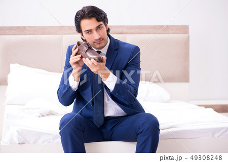 Young handsome businessman choosing shoes at home Young handsome businessman choosing shoes at home 49308248