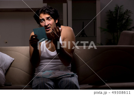 Young man calculating expences night at home  49308611
