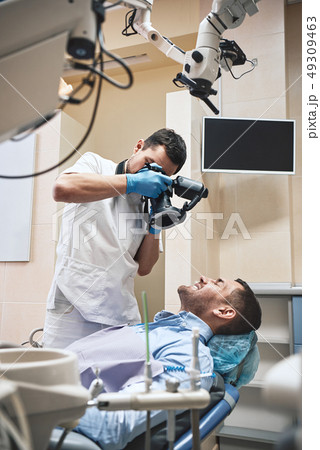 Gentle, high-quality dental care. Dentist with camera making shots of patient's smile after Gentle, high-quality dental care. Dentist with camera making shots of patient's smile after 49309463