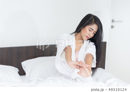Asian Woman stretching in bed with her arms 49310124