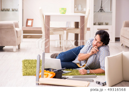Young handsome man repairing chair at home  49316568