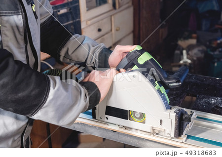 Close-up manual circular power saw in the hands of a worker in a home workshop. Starting a business 49318683