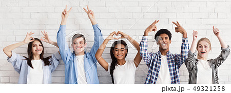 Students gesturing with hands over white wall Students gesturing with hands over white wall 49321258