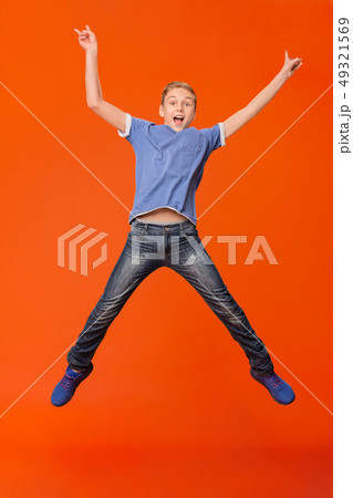 Happy boy jumping and raising his hands up Happy boy jumping and raising his hands up 49321569