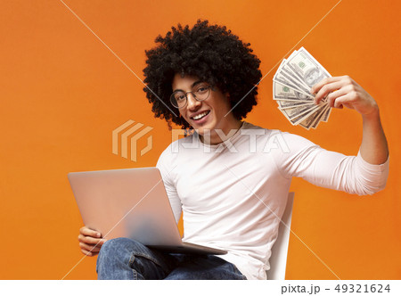 Happy guy working on laptop and showing bunch of money Happy guy working on laptop and showing bunch of money 49321624