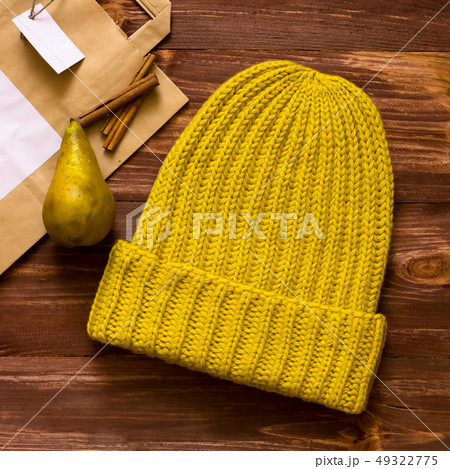 Warm soft yellow hat made by hand on a dark Board next with pears and cinnamon sticks 49322775
