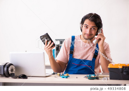 Young male contractor repairing computer   49334808