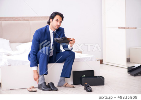 Young handsome businessman choosing shoes at home Young handsome businessman choosing shoes at home 49335809