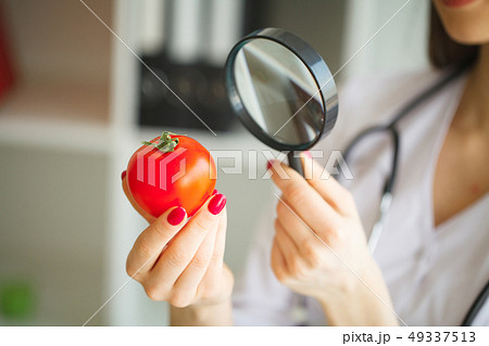 Diet Concept. Dietitian Inspecting Vegetables with Magnifying Glass 49337513