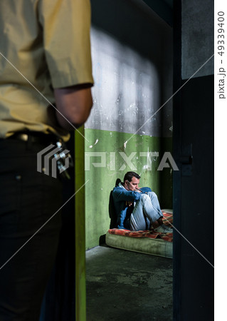 Young male prisoner sitting alone in an obsolete prison cell Young male prisoner sitting alone in an obsolete prison cell 49339400