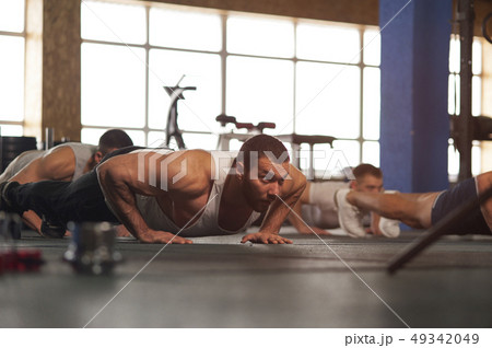 Small Group of Muscular Male Adults Warming Up Training Push Ups. Small Group of Muscular Male Adults Warming Up Training Push Ups. 49342049