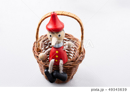Pinochio toy figurine sitting in a basket Pinochio toy figurine sitting in a basket 49343639