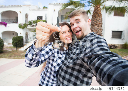 Real estate and property concept - Happy couple holding keys to new home and house miniature 49344382