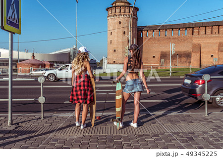 Two girlfriends girl, against background of road transition, stand with skateboards, longboard, view 49345225