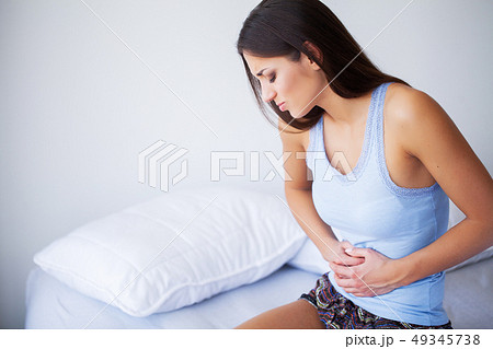 Stomach Pain. Unhealthy young woman with stomachache leaning on the bed at home Stomach Pain. Unhealthy young woman with stomachache leaning on the bed at home 49345738