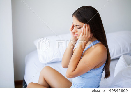 Head pain. Attractive young woman wake up on her bed looking unhappy and feeling sick. Head pain. Attractive young woman wake up on her bed looking unhappy and feeling sick. 49345809