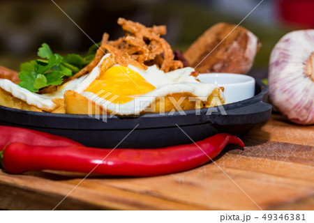 Nutricious meal with fried egg, sausages, beans, onion rings, chili pepper Nutricious meal with fried egg, sausages, beans, onion rings, chili pepper 49346381