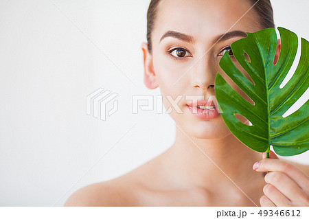 Skincare. Beautiful Woman Portrait on White Background With Clean Skin and Green Leaf in Hand Skincare. Beautiful Woman Portrait on White Background With Clean Skin and Green Leaf in Hand 49346612