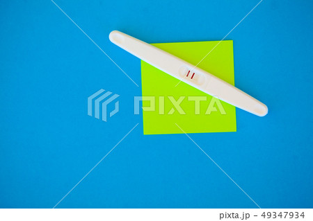 Pregnancy test with a positive result lying on a blue background. 49347934