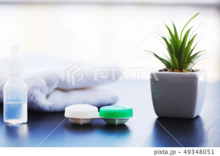 Vision Contact Lenses. Bottle with lens solution and case on wood table. 49348051