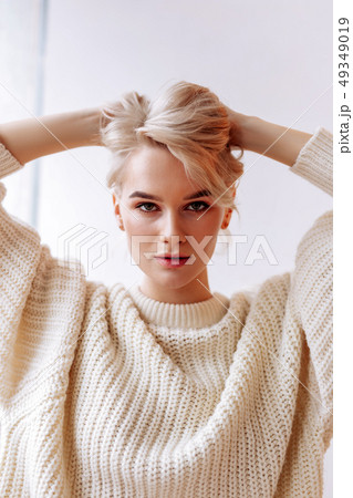 Beautiful young woman standing near white wall in the bedroom Beautiful young woman standing near white wall in the bedroom 49349019