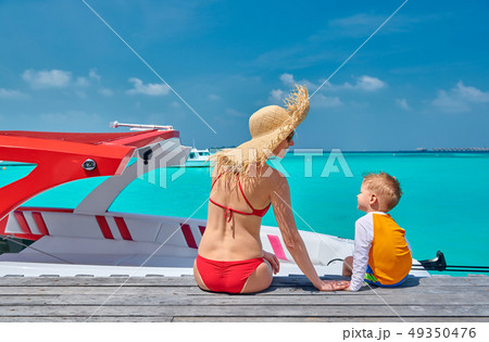 Toddler boy with mother sitting on wooden jetty 49350476