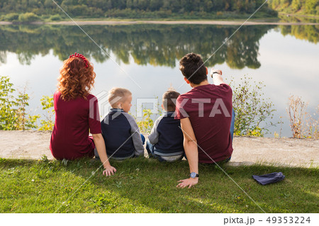 Childhood and nature concept - Family with little sons sitting on the green grass 49353224