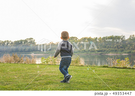 Chilhood, people concept - young boy playing with soap bubbles 49353447