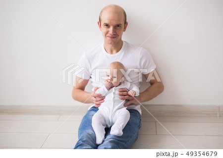 Infant, family and children concept - Bald father takes care of his little baby Infant, family and children concept - Bald father takes care of his little baby 49354679