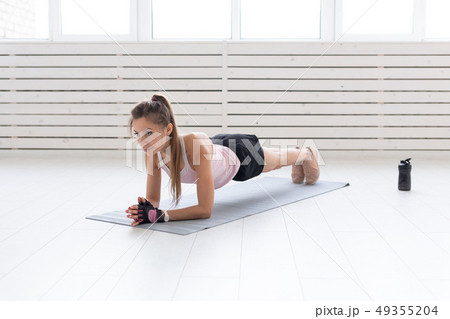 Sport, yoga and people concept - a young woman is doing a plank, taking a balance 49355204