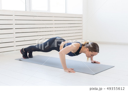 People, healthy and sport concept- Young sporty attractive woman doing push ups People, healthy and sport concept- Young sporty attractive woman doing push ups 49355612