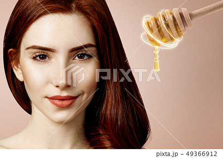 Young redhead woman and honey spoon prepare for facial mask. Young redhead woman and honey spoon prepare for facial mask. 49366912