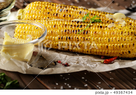 Kitchen table with grilled sweet corn cob under 49367434