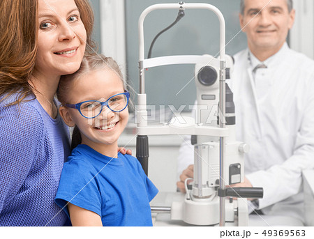 Patients smiling, posing with ophthalmologist in clinic. Patients smiling, posing with ophthalmologist in clinic. 49369563