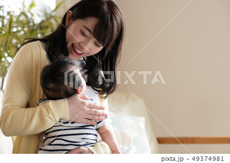 赤ちゃんをあやす若い母親 笑顔 日本人親子の写真素材