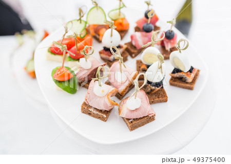 Buffet table. Assortment of canapes. Banquet service in restaurant. Catering food, snacks on white Buffet table. Assortment of canapes. Banquet service in restaurant. Catering food, snacks on white 49375400