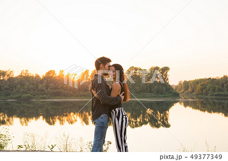 Romantic and people concept - young couple hugging together near the river or lake and enjoying 49377349