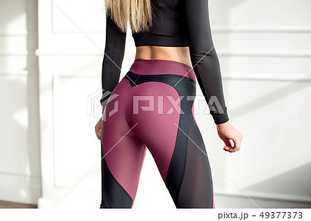 Young slim woman with an athletic body long blonde hair wearing in black sports sportswear top and Young slim woman with an athletic body long blonde hair wearing in black sports sportswear top and 49377373