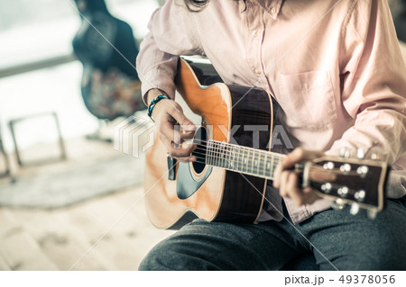 Experienced attentive musician wearing light shirt and touching strings 49378056