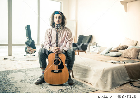 Long-haired young musician resting in stylish bedroom 49378129