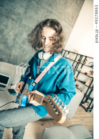 Careless long-haired man being inspired while playing music 49378663