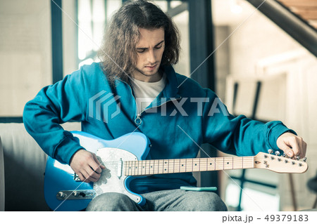 Concentrated good-looking unusual guy setting up strings on his electronic guitar 49379183