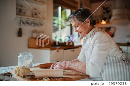 Elderly woman making cakes in a kitchen at home. Copy space. 49379238