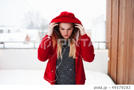 A portrait of young girl or woman with earphones outdoors, listening to music. 49379282