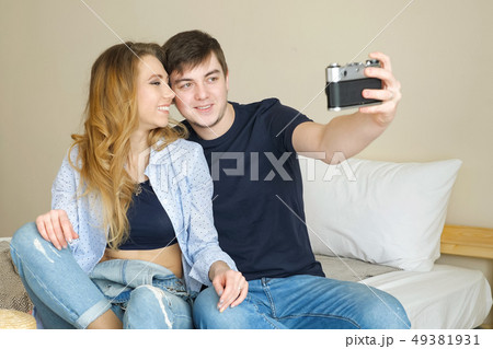 girl guy sit on bed make selfie with old camera posing 49381931