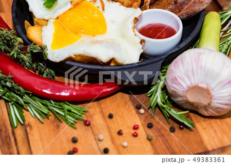 Nutricious meal with fried egg, onion rings, chili pepper and sauce in frying pan 49383361