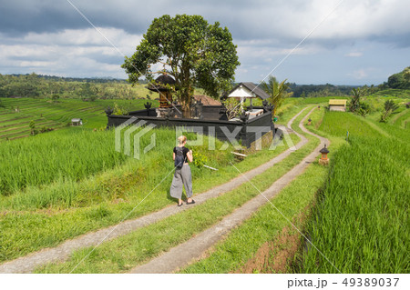 Female tourist walking a path among Jatiluwih rice terraces and plantation in Bali, Indonesia. Female tourist walking a path among Jatiluwih rice terraces and plantation in Bali, Indonesia. 49389037