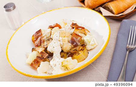 Baked potatoes with cauliflower, bacon, cheese sauce 49396094